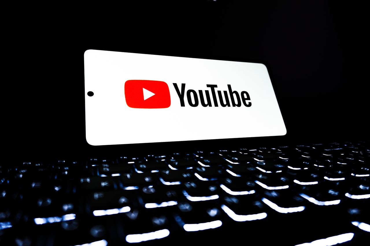 Icône de l’application YouTube affichée sur un smartphone posé sur un clavier éclairé, représentant les médias numériques et le streaming en ligne.